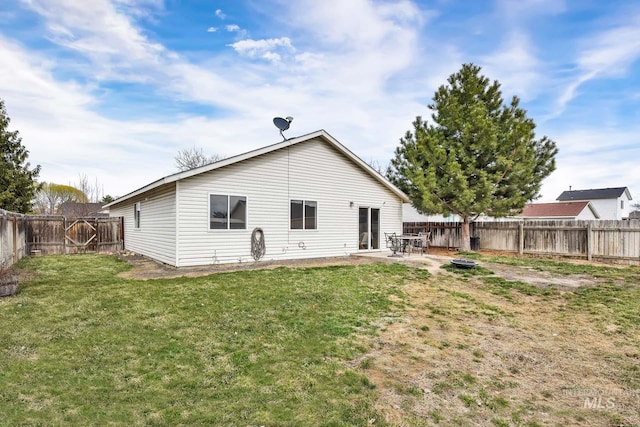 rear view of property featuring a yard, a patio, and a fenced backyard