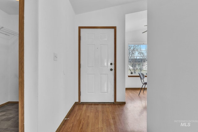 foyer with baseboards, wood finished floors, and vaulted ceiling