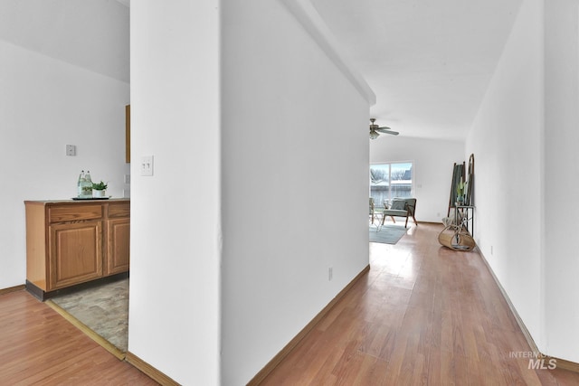 corridor with baseboards and light wood-style floors