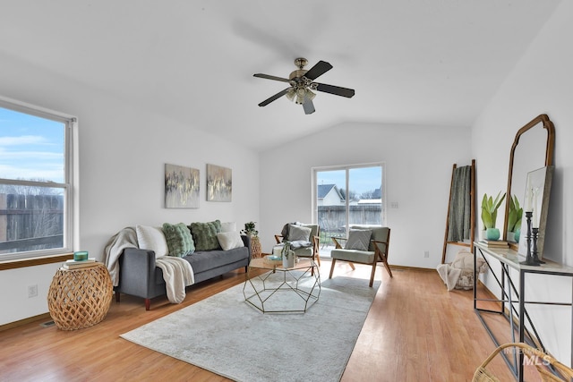 living area with vaulted ceiling, baseboards, light wood finished floors, and ceiling fan