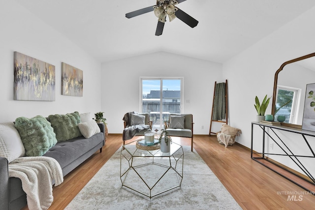 living area featuring lofted ceiling, wood finished floors, and a ceiling fan