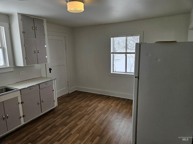 kitchen featuring white fridge, dark hardwood / wood-style floors, sink, and white cabinets