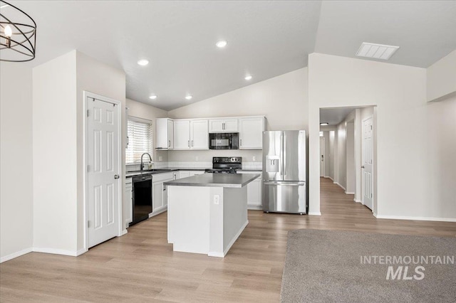 11177 Champlain Pl Unit 9, Caldwell, ID 83605 - kitchen featuring black appliances, lofted ceiling, light wood-type flooring, white cabinetry, and a center island
