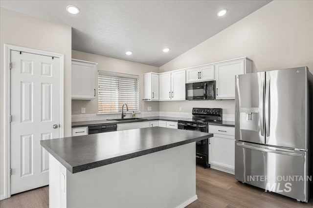 11177 Champlain Pl Unit 9, Caldwell, ID 83605 - kitchen featuring black appliances, dark countertops, vaulted ceiling, white cabinetry, and wood finished floors
