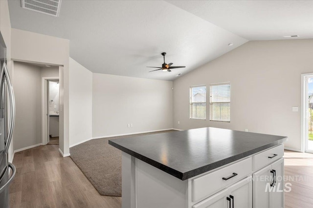 11177 Champlain Pl Unit 9, Caldwell, ID 83605 - kitchen featuring dark countertops, ceiling fan, light wood-style flooring, lofted ceiling, and white cabinets