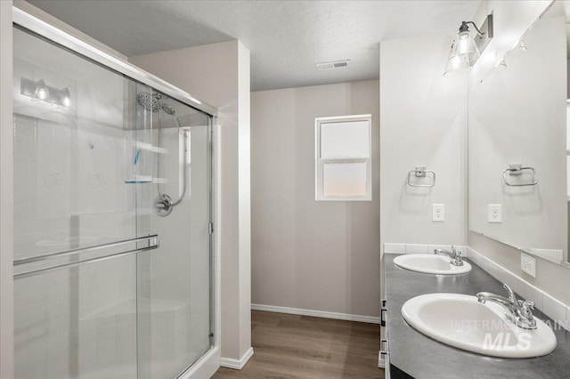 11177 Champlain Pl Unit 9, Caldwell, ID 83605 - full bathroom with a shower stall, wood finished floors, double vanity, and a textured ceiling