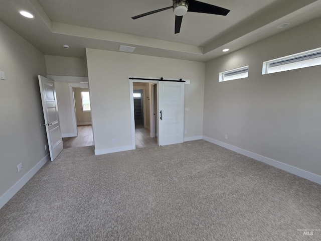 563 Full Moon Way, Twin Falls, ID 83301 - unfurnished bedroom with light colored carpet, a barn door, recessed lighting, a raised ceiling, and ceiling fan