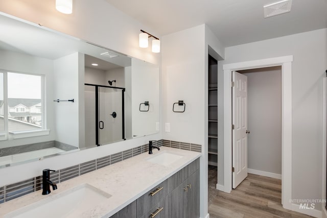 bathroom featuring wood-type flooring, vanity, and a shower with shower door