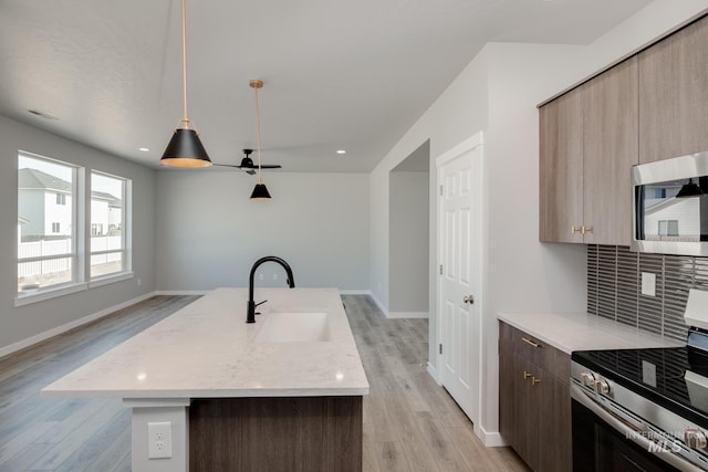 kitchen with a center island with sink, light hardwood / wood-style floors, sink, and stainless steel appliances