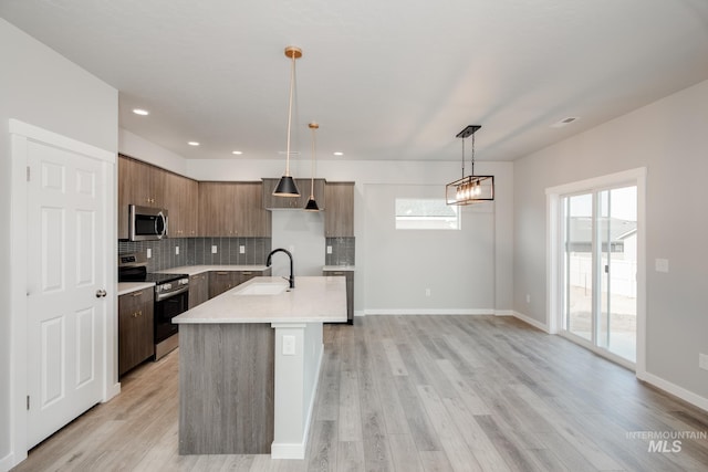 kitchen featuring light hardwood / wood-style floors, a healthy amount of sunlight, hanging light fixtures, and appliances with stainless steel finishes