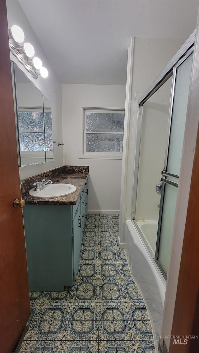 bathroom with a wealth of natural light, tile patterned flooring, shower / bath combination with glass door, and vanity