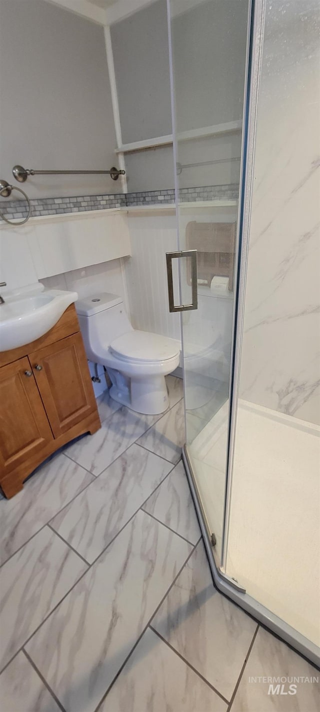 bathroom featuring vanity, toilet, and a shower with door