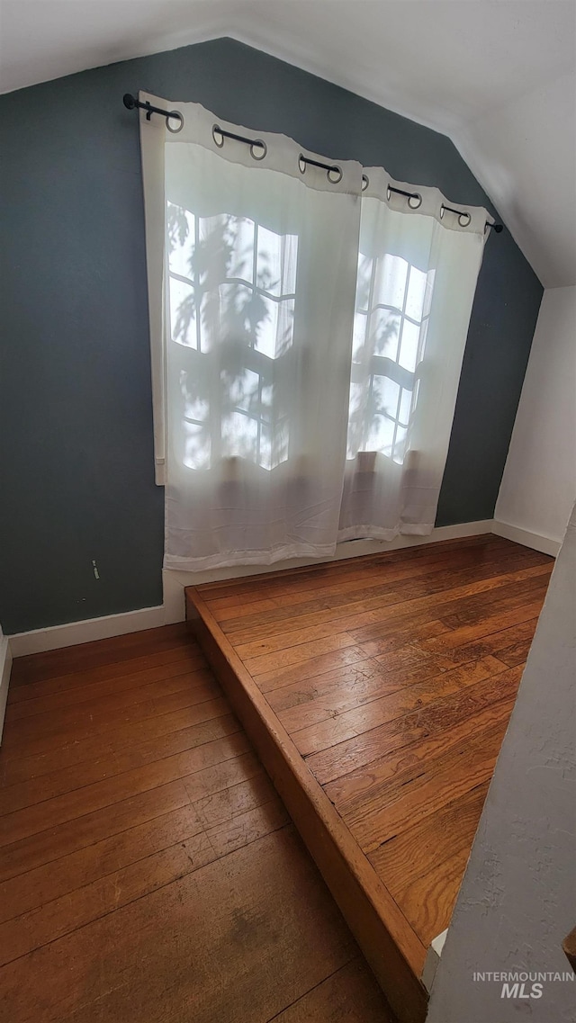 bonus room with vaulted ceiling and dark wood-type flooring