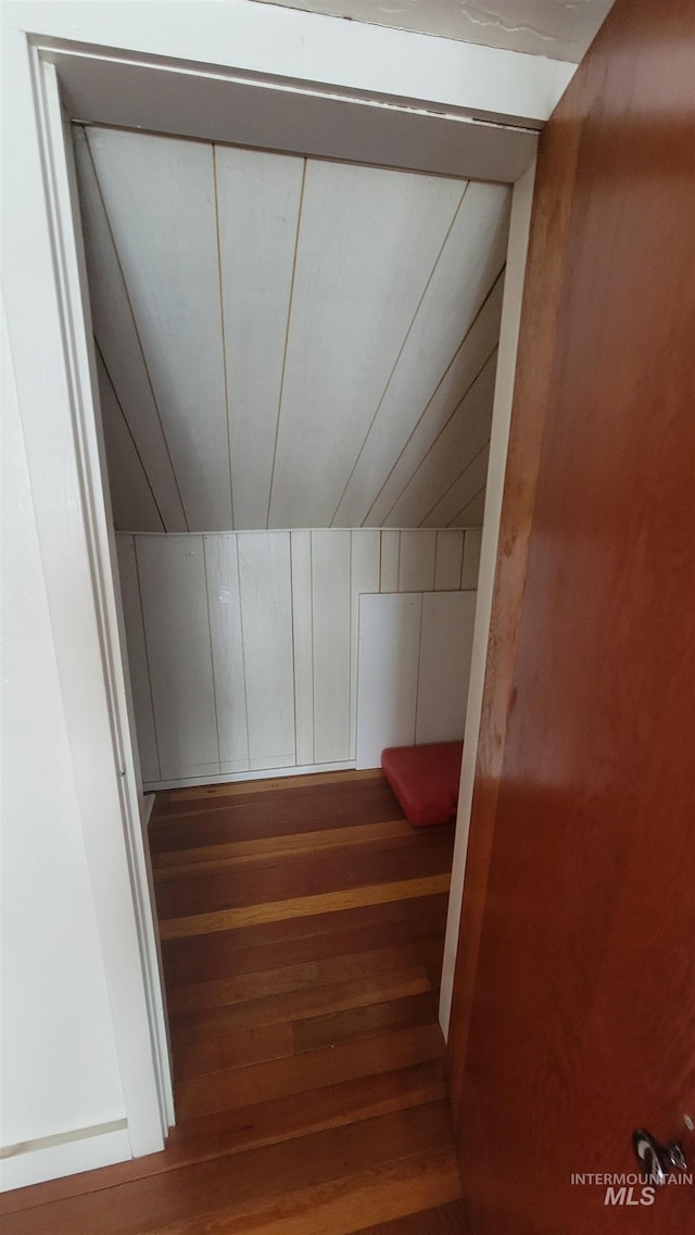 stairs featuring vaulted ceiling, wood walls, and hardwood / wood-style floors