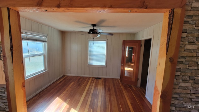 empty room with wood walls, dark hardwood / wood-style floors, and ceiling fan