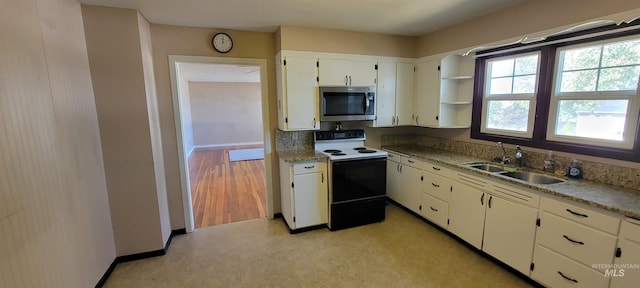 kitchen with electric stove, light hardwood / wood-style floors, sink, and white cabinetry