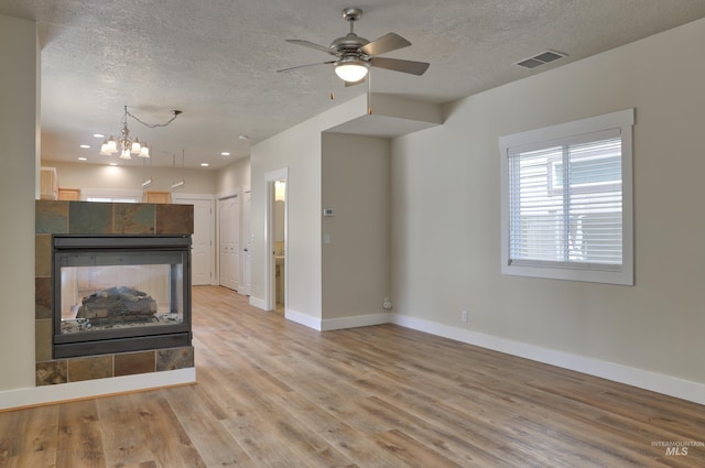 1421 S Denver Ave, Boise, ID 83706 - unfurnished living room featuring a textured ceiling, baseboards, ceiling fan, light wood-type flooring, and a chandelier
