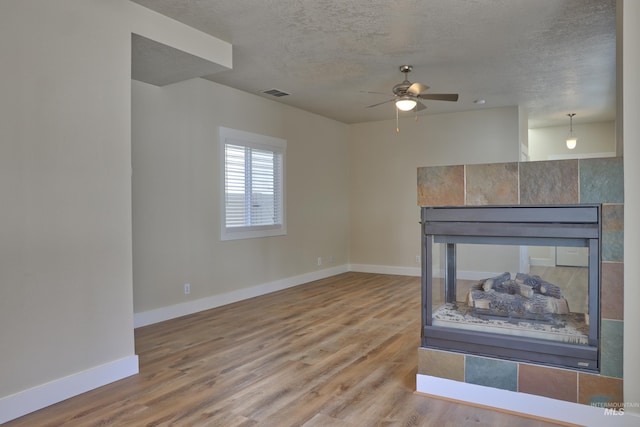 1421 S Denver Ave, Boise, ID 83706 - unfurnished living room with a ceiling fan, wood finished floors, baseboards, a textured ceiling, and a tile fireplace