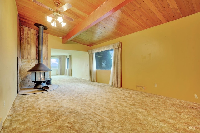 unfurnished living room featuring carpet flooring, a wood stove, beamed ceiling, and wood ceiling