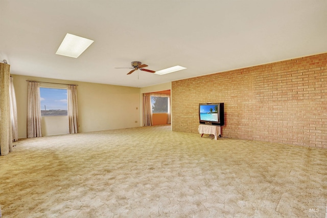 unfurnished living room with carpet, ceiling fan, and brick wall