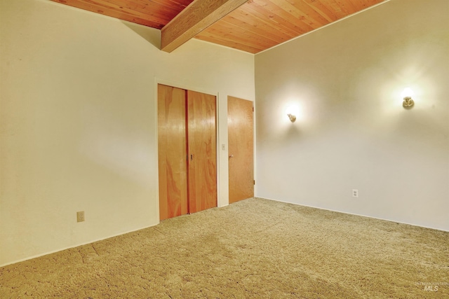 carpeted spare room featuring beamed ceiling and wood ceiling