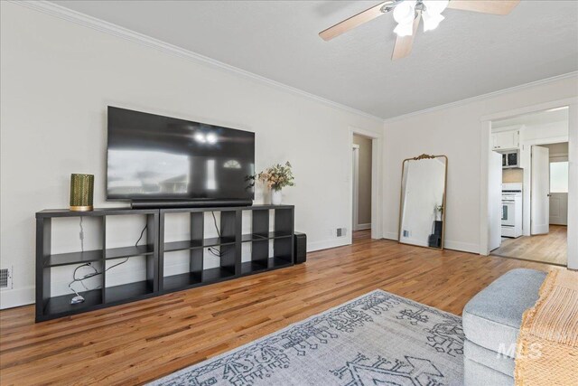 living area featuring crown molding, a ceiling fan, baseboards, and wood finished floors