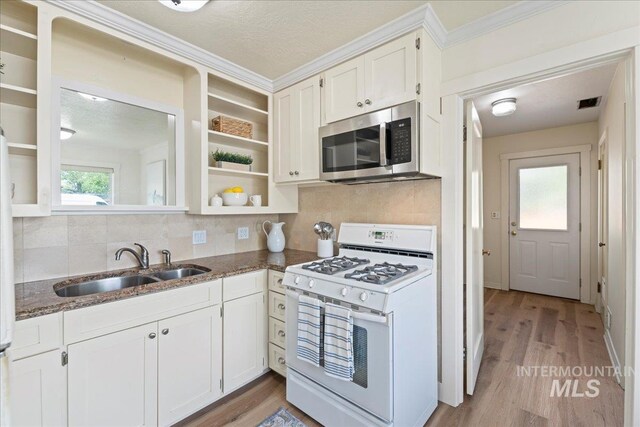 kitchen featuring open shelves, white gas range oven, stainless steel microwave, a sink, and backsplash