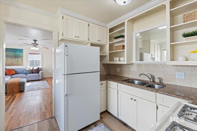 kitchen with freestanding refrigerator, open shelves, crown molding, and a sink