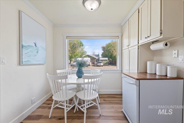 dining room featuring crown molding, baseboards, and light wood-type flooring
