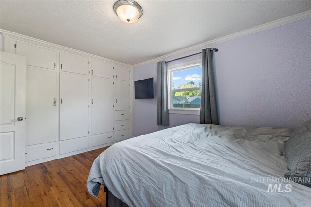 bedroom featuring crown molding, wood finished floors, and a closet