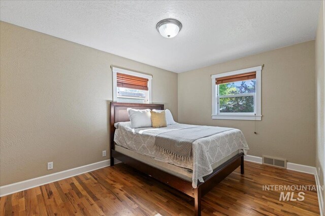 bedroom featuring visible vents, baseboards, and wood finished floors