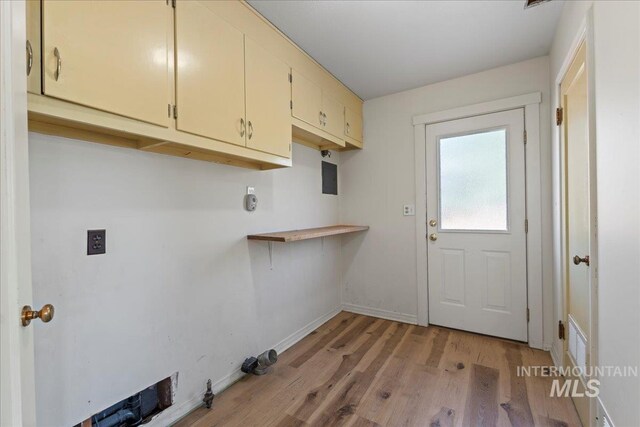 laundry room featuring light wood-type flooring, cabinet space, and baseboards