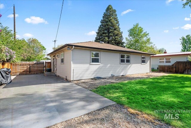 rear view of house with fence, a yard, and gravel driveway