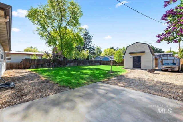 view of yard with an outdoor structure, a fire pit, a fenced backyard, a storage unit, and a patio area