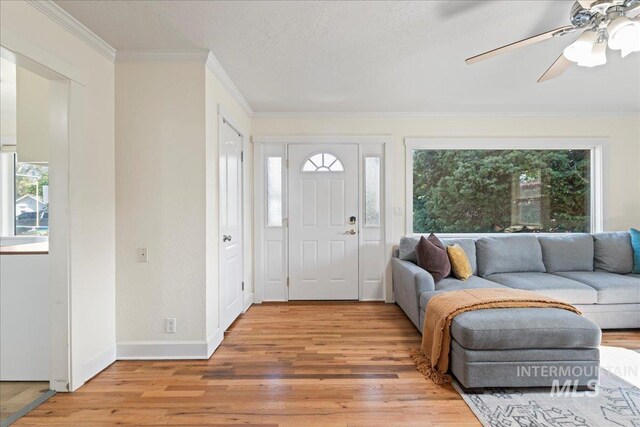 foyer entrance featuring baseboards, ornamental molding, light wood-style flooring, and ceiling fan