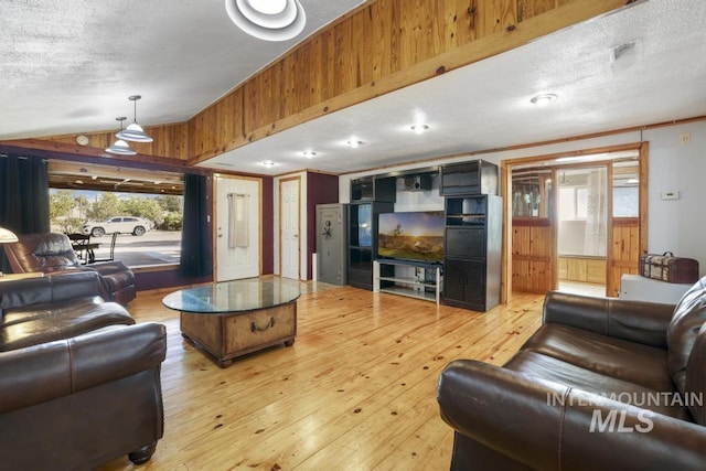 living room featuring light wood-style flooring, a textured ceiling, and vaulted ceiling
