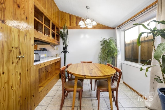 dining space featuring an inviting chandelier, light tile patterned flooring, and vaulted ceiling
