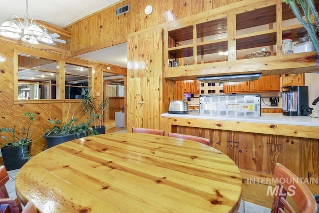 dining space featuring a notable chandelier, wood walls, and visible vents