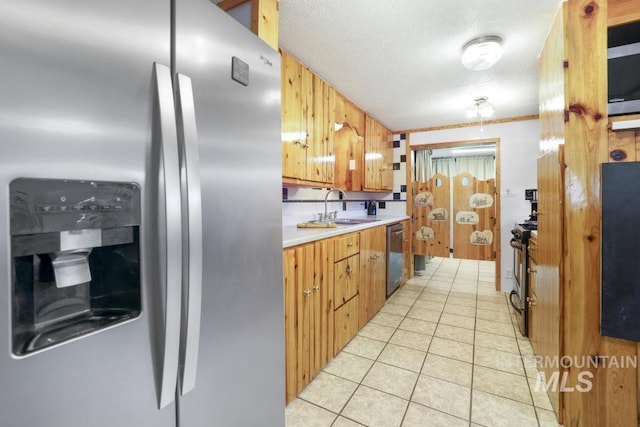 kitchen featuring a textured ceiling, a sink, light countertops, light tile patterned floors, and stainless steel appliances