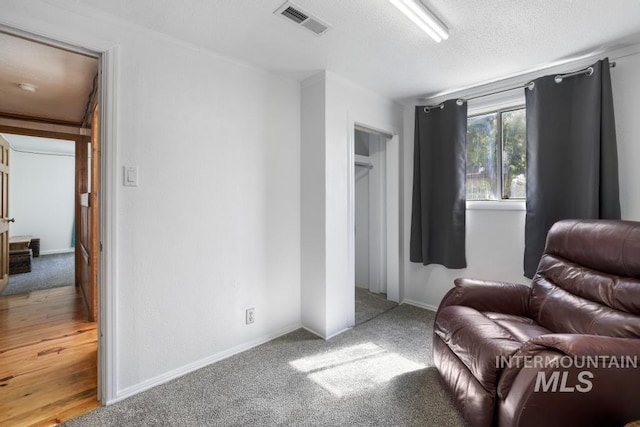 living area with baseboards, carpet, a textured ceiling, and visible vents