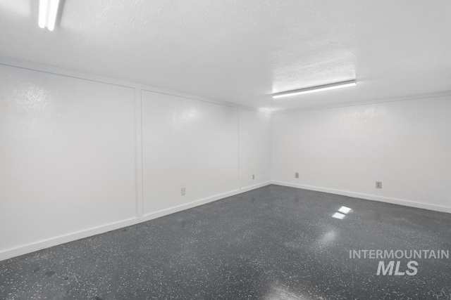 finished below grade area featuring a textured ceiling and baseboards