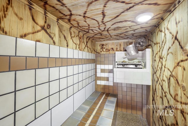 full bath featuring tile patterned floors, tiled shower, and tile walls