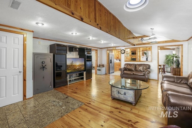 living room featuring light wood-style floors, lofted ceiling, and visible vents