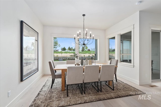 dining room with light wood finished floors, visible vents, baseboards, and a notable chandelier