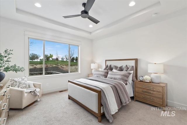 bedroom featuring light carpet, visible vents, baseboards, a tray ceiling, and recessed lighting