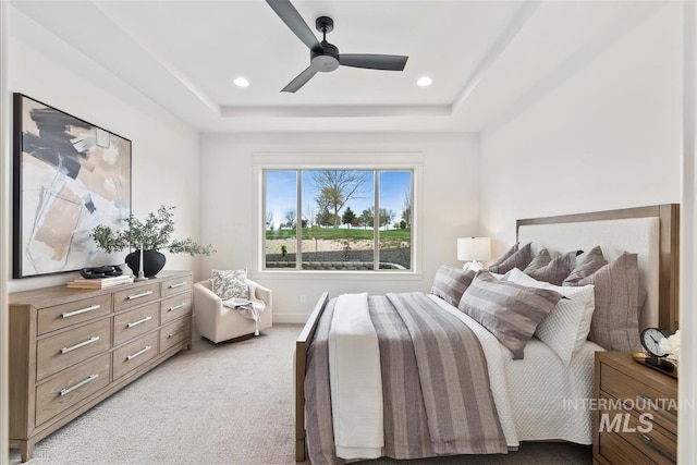 bedroom with a ceiling fan, a tray ceiling, light carpet, and recessed lighting