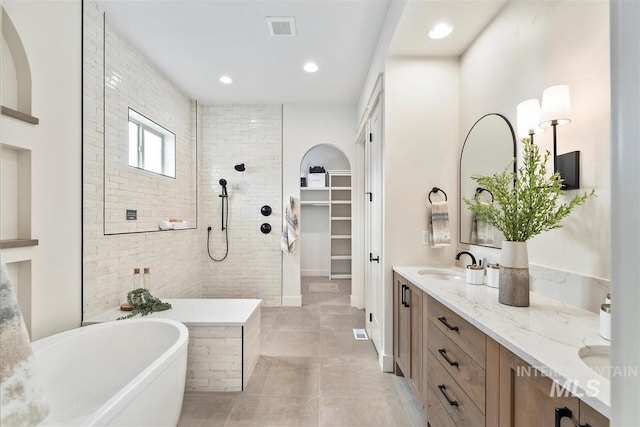 bathroom featuring a sink, visible vents, a freestanding bath, double vanity, and walk in shower