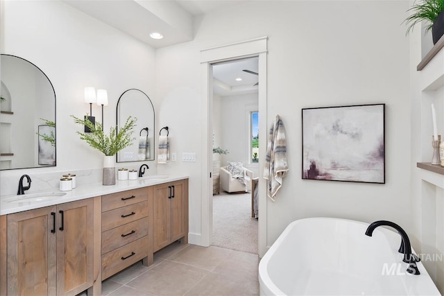 bathroom featuring double vanity, a soaking tub, ensuite bath, tile patterned flooring, and a sink