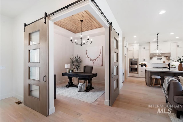 interior space with recessed lighting, light wood-style flooring, baseboards, and a barn door