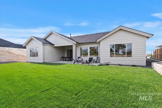 back of house featuring a shingled roof, a patio, and a lawn